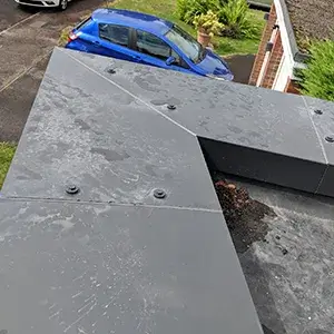 A blue car parked in a driveway next to a house.
