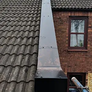 A chimney on the side of a brick building.