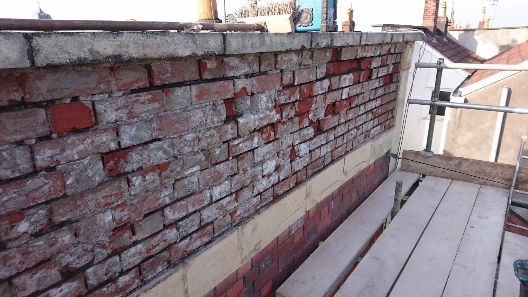 A red brick wall next to a metal railing.