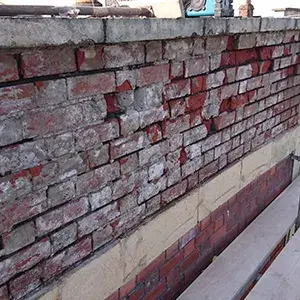 A bench sitting in front of a brick wall.