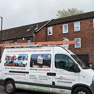 A white van parked in front of a brick building.
