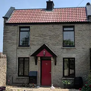 A brick house with a red door and a red roof.